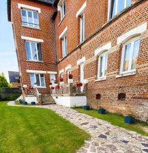 a brick building with windows and a grass yard at L'échappée Verte en Thiérache in Martigny