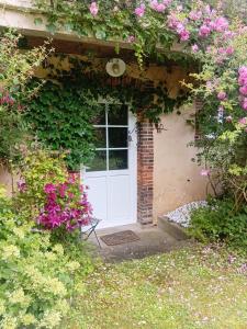 a white door with flowers on a building at Le Tilleul du Perche - Jardin clos - Fibre - Télétravail - Parking privé in La Ventrouze +17 photos