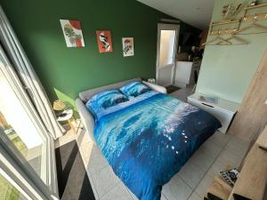 a bedroom with a blue bed in a green wall at Le Petit Studio de Merlimont in Merlimont