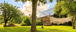 a hammock hanging from a tree in front of a house at Penty horizon de Brocéliande in Augan