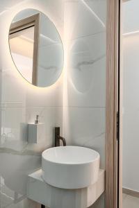 a white bathroom with a sink and a mirror at The Luxe Residence in episkopi-chania