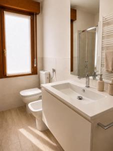 a white bathroom with a toilet and a sink at residenza MINERVA & swimming pool in Aprilia Marittima