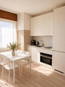 a white kitchen with a white table and chairs at residenza MINERVA & swimming pool in Aprilia Marittima