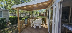 a wooden deck with a table and chairs on it at Mobil home 6 personnes confort Océan climatisé camping avec piscine Agde in Agde
