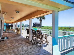 a deck with chairs and tables and a view of the ocean at Pelicans and Palms home in Crystal Beach