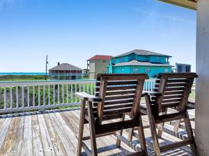 two chairs sitting on a deck with a house in the background at Pelicans and Palms home in Crystal Beach