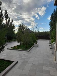 eine Terrasse mit Bäumen und Sträuchern und einem bewölkten Himmel in der Unterkunft Hotel KREZ in Qysylorda