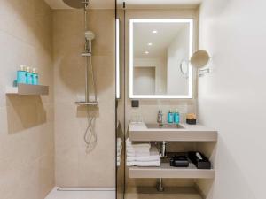 a bathroom with a sink and a mirror and a shower at Novotel Tallinn in Tallinn