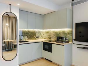 a kitchen with white cabinets and a sink and a mirror at Novotel Tallinn in Tallinn