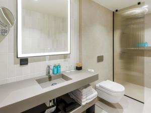 a bathroom with a sink and a toilet and a mirror at Novotel Tallinn in Tallinn +116 photos