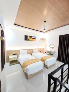 two beds in a room with white walls at Lodjisvarga Villa Yogyakarta in Sleman +19 photos