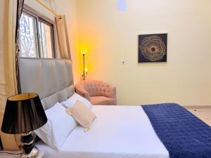 a bedroom with a bed and a chair and a window at Modern Studios Apartments in Juffair and Exhibition in Manama