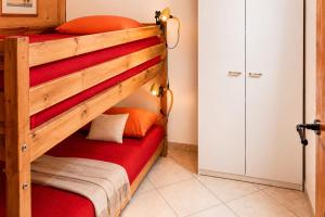 a bedroom with a bunk bed with red sheets at Trebbiano Rubicone in Gravedona