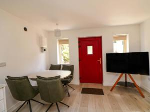a dining room with a red door and a table with chairs at The Mews Suskar in Glendarragh