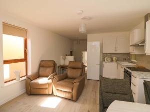 a living room with two chairs and a kitchen at The Mews Suskar in Glendarragh