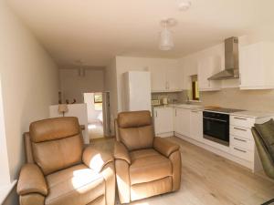 a living room with two chairs and a kitchen at The Mews Suskar in Glendarragh +7 photos
