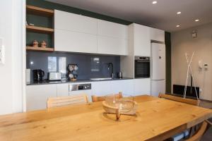 a kitchen with a wooden table and white cabinets at Brand-New Spacious 3 Bd Apt in Piraeus in Piraeus