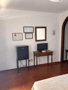 a room with a desk and a television on a wall at Hotel Apolo XI in Tahivilla