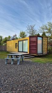 a picnic table in front of a tiny house at Cubil Amarillo. Casa conteiner 1 dormitorio in General Roca