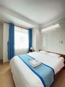 a bedroom with a large bed with blue curtains at Hotel Lê My in Can Tho +11 photos