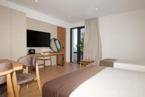a hotel room with a bed and a desk and a tv at Safir Luxury Suites in Sarandë