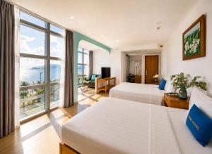 a hotel room with two beds and a large window at Prime New Hotel in Nha Trang