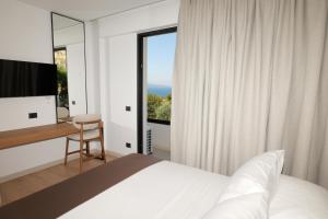 a bedroom with a bed and a desk and a window at Safir Luxury Suites in Sarandë +79 photos