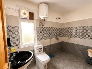 a bathroom with a sink and a toilet and a window at Kabir's Chalet Shangarh in Shangarh