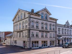 a large building on a street with a car parked in front at Marin Hotel Sylt GmbH in Westerland