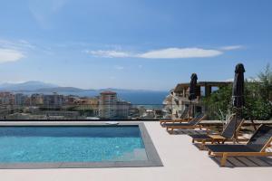 a pool with chaise lounge chairs and a view of the ocean at Safir Luxury Suites in Sarandë
