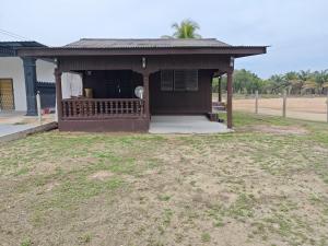 a small house with a porch in a field at Rooma Kayu in Kampong Alor Fatimah