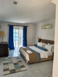 a bedroom with a large bed with blue curtains at Ladonia Hotels Zemda in Gümüşlük