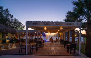 a restaurant with tables and chairs on a wooden deck at Ladonia Hotels Zemda in Gümüşlük