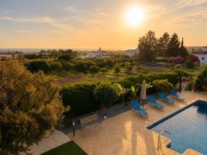 an outdoor swimming pool with chairs and the sun setting at Mariandy Villa 2 in Coral Bay +7 photos