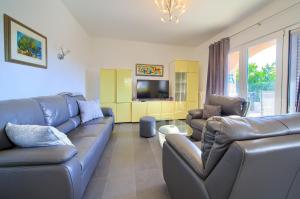 a living room with leather couches and a tv at Apartmani Kirinčić in Krk