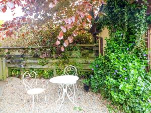 two chairs and a table in front of a garden at The Mews Derrybawn in Glendarragh