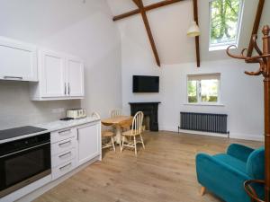 a kitchen and dining room with a table and a blue couch at The Mews Derrybawn in Glendarragh
