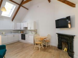 a kitchen with a table and chairs and a television at The Mews Derrybawn in Glendarragh +14 photos