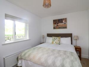a white bedroom with a bed and a window at The Mews Derrybawn in Glendarragh