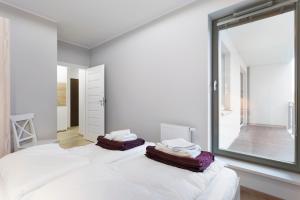 a white bedroom with a large window and a bed at Spokojny i komfortowy apartament wśród zieleni in Wrocław