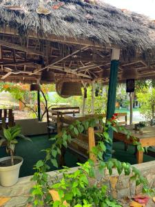 a restaurant with a thatched roof with a table and benches at African Treasure kokrobite in Kokrobite