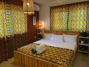 a bedroom with a large bed with a yellow wall at African Treasure kokrobite in Kokrobite