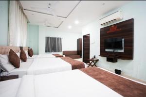 a hotel room with two beds and a flat screen tv at Mangal Hotel & Resorts Pool in Udaipur