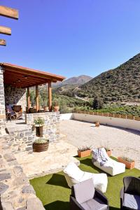 a backyard with a stone patio with chairs and a fireplace at Zefki Stone Villa in Fodele