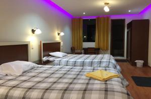 2 Betten in einem Hotelzimmer mit violetten Lichtern in der Unterkunft Casa Suite in Juliaca