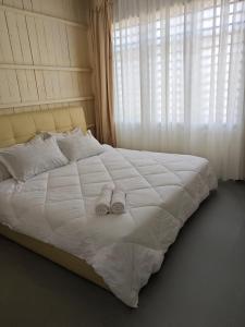 a large white bed with two towels on it at Rooma Kayu in Kampong Alor Fatimah