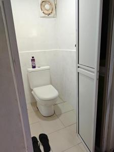 a bathroom with a toilet and a white tile floor at Rooma Kayu in Kampong Alor Fatimah
