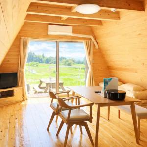a dining room with a table and a large window at 自然満喫 野上平ロッジ in Kirishima
