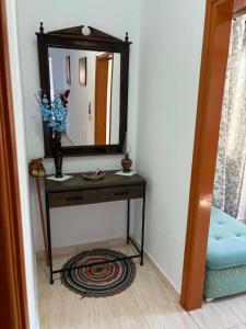 a table with a mirror and a vase with flowers at Maria's Apartment in Lixouri