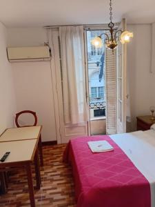 a bedroom with a bed and a table and a window at Hotel guido palace in Buenos Aires